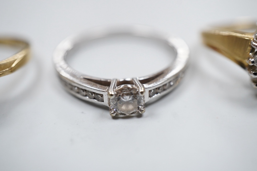 A collection of three rings, comprising: a ring, set with a brilliant-cut diamond weighing approximately 0.20 carats, to shoulders set with smaller brilliant-cut diamonds totalling approximately 0.16 carats, mounted in 9